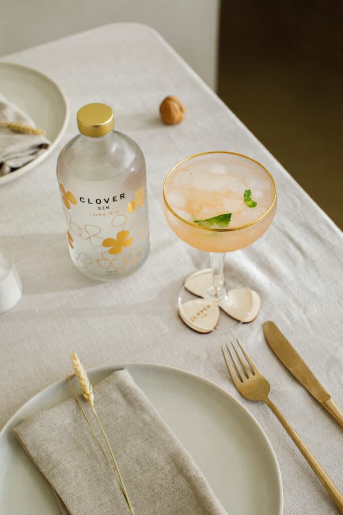 Clover Gin cocktail in coupeglas met munt en ijs op stijlvol gedekte tafel met gouden bestek