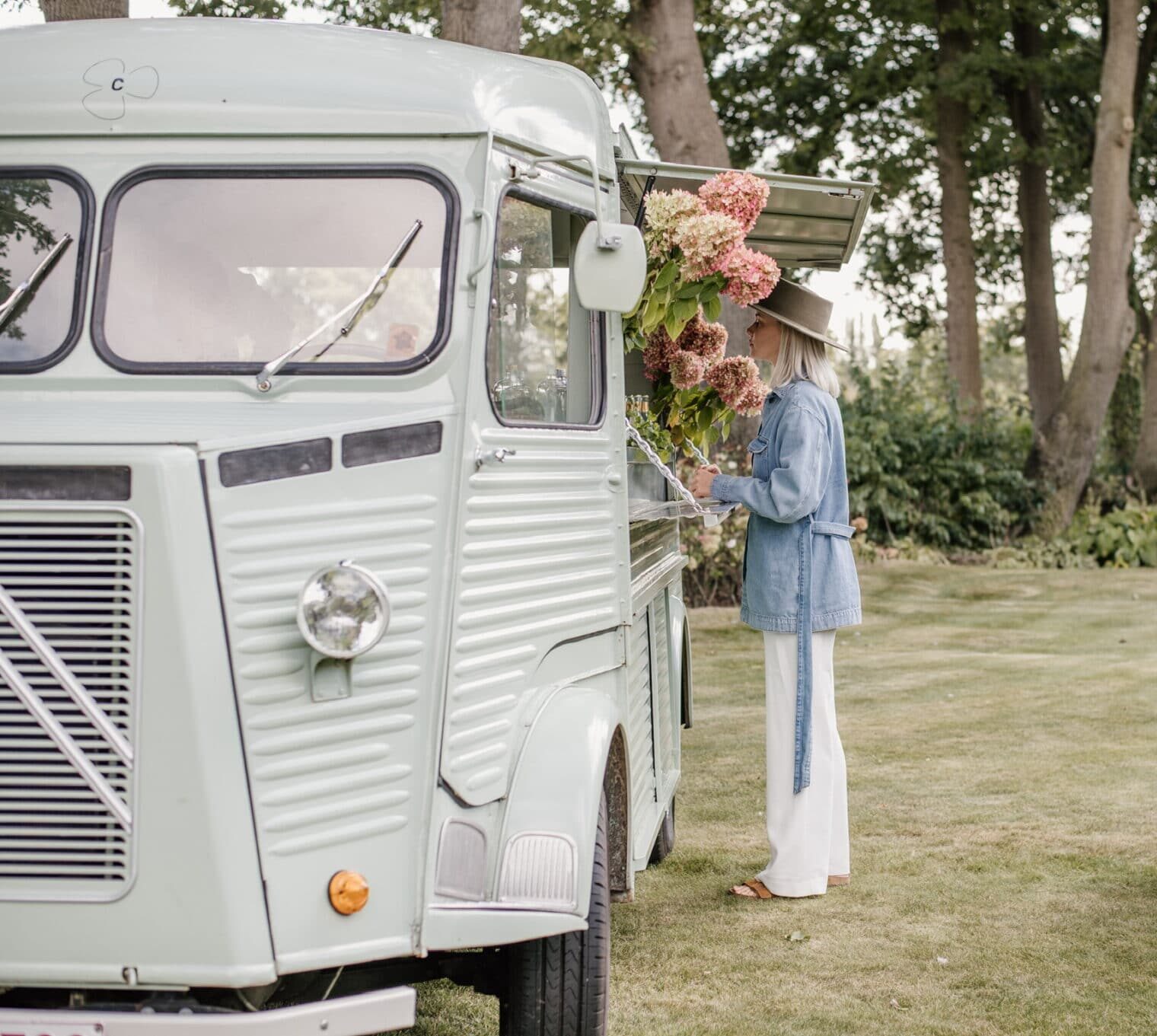 Clover Gin mobiele cocktailbar in vintage bus tijdens buiten event met vrouw die drankje bestelt